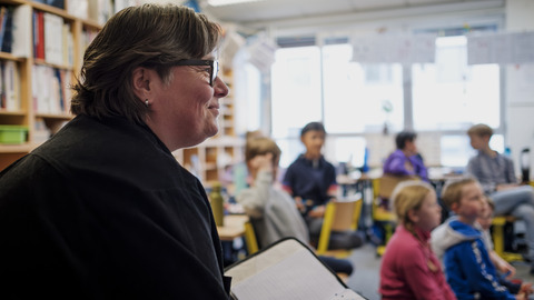 Lehrerin blickt in Klassenraum und lächelt