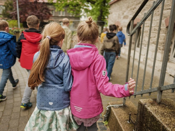 Kinder laufen Arm in Arm über den Schulhof